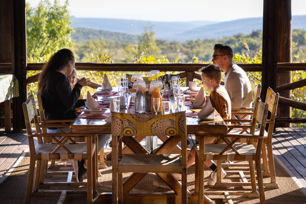 a family having breakfast on the deck of. their lodge