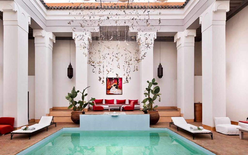 Sun loungers and seating next to a small pool surrounded by white pillars in Morocco.