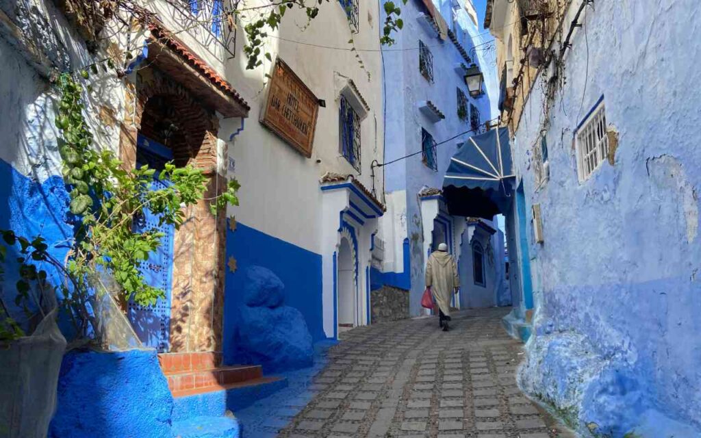 A man walks along a blue alleyway in Chefchaouen.