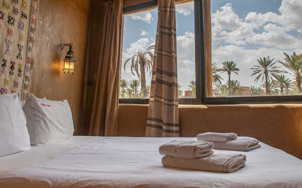 A double bedroom in a lodge, trees can be seen through the windows.