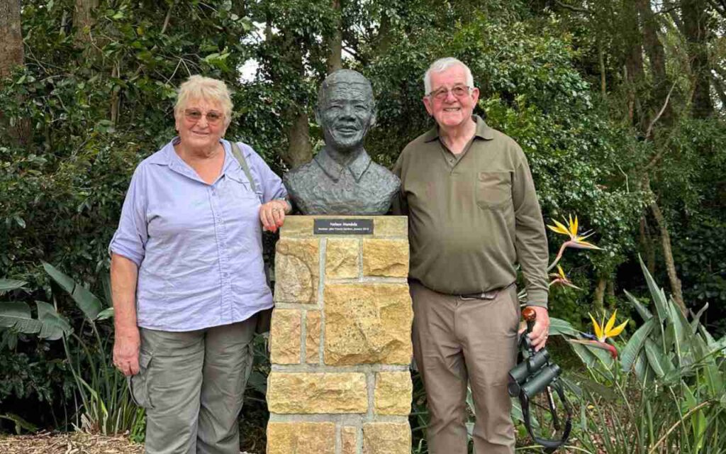 A couple stand beside a statue.