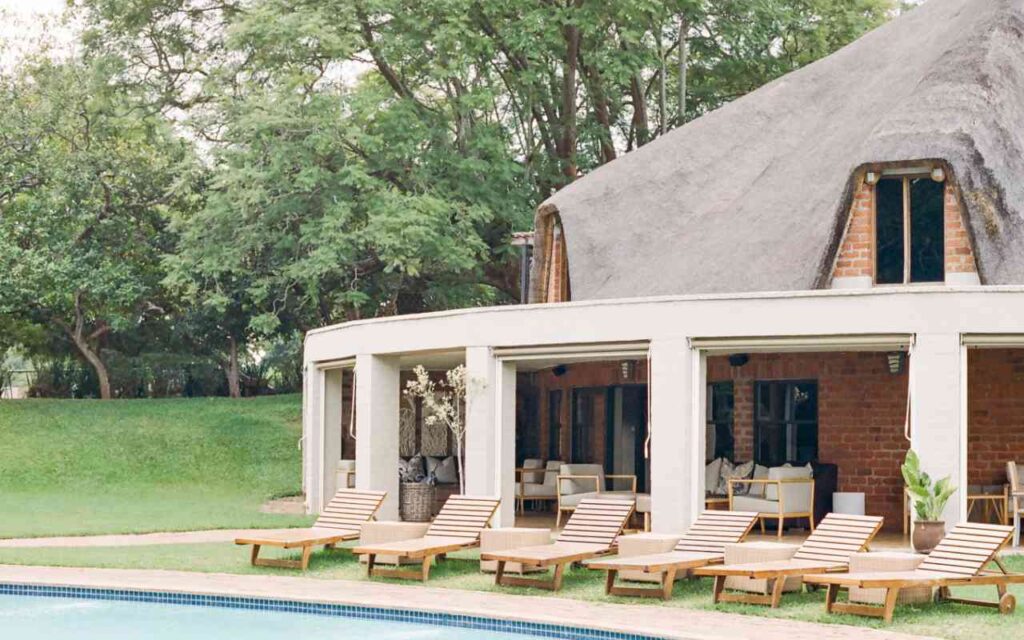 Two storey accommodation with outdoor lounge seating next to a pool.