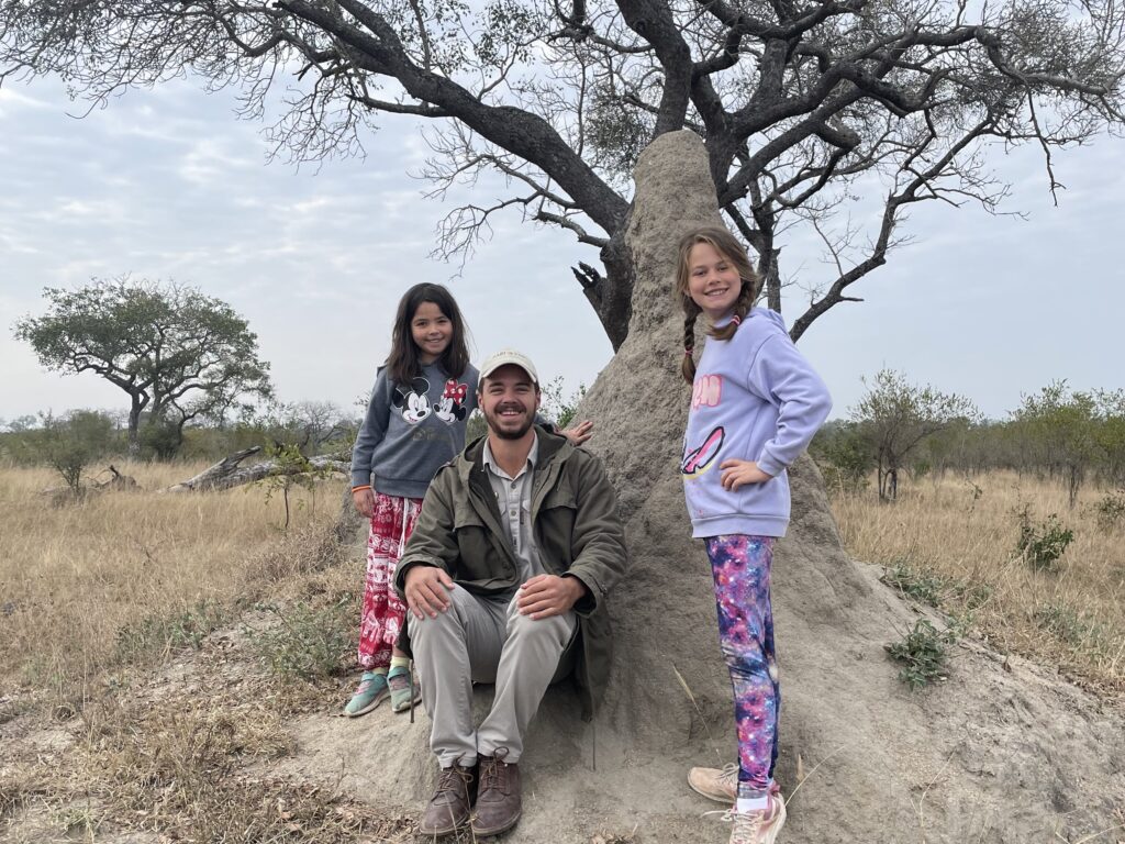 A family stand by a tree on safari.