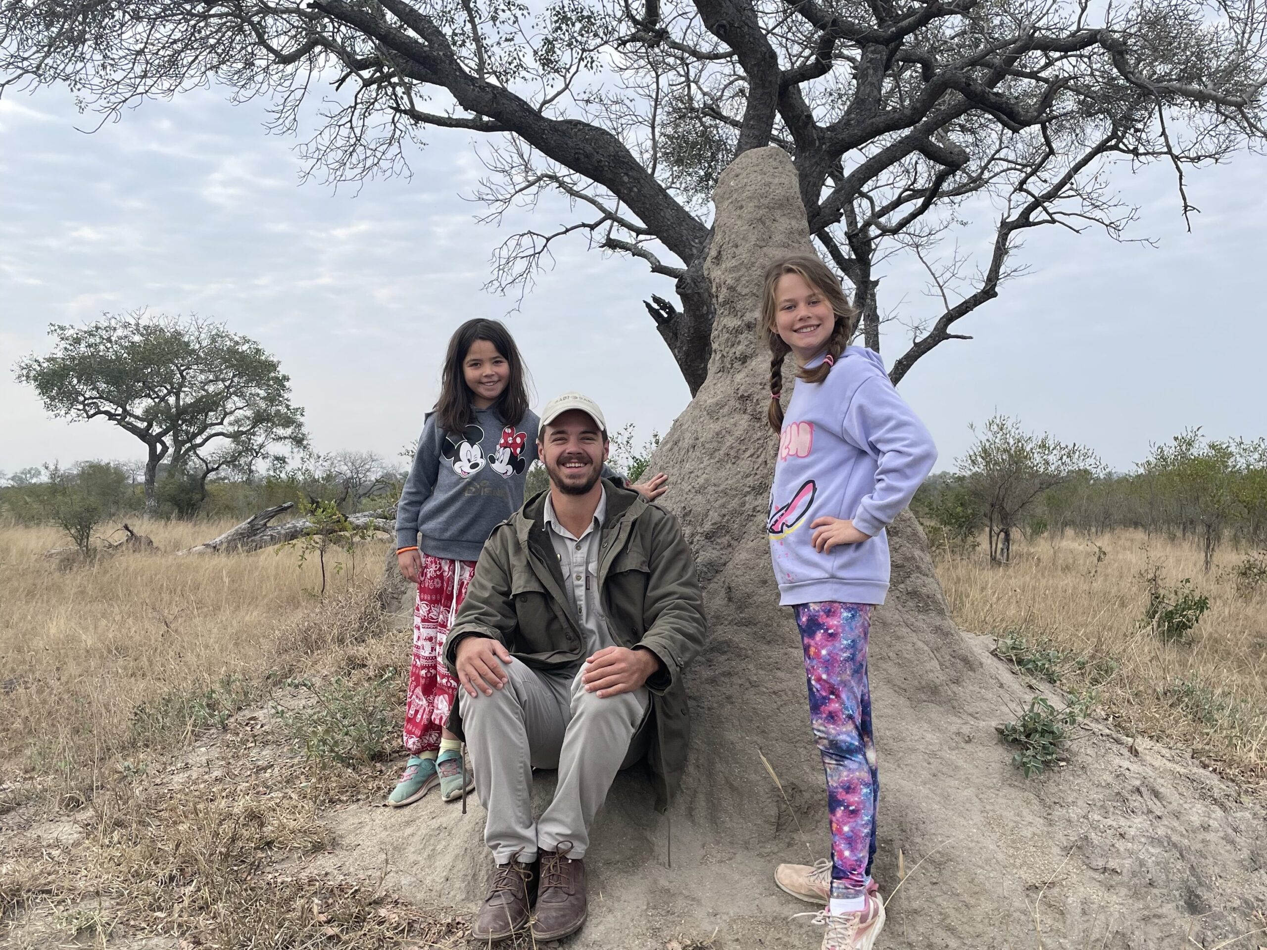 A family stand by a tree on safari.